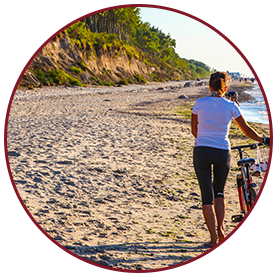kobieta prowadzi rower na plaży